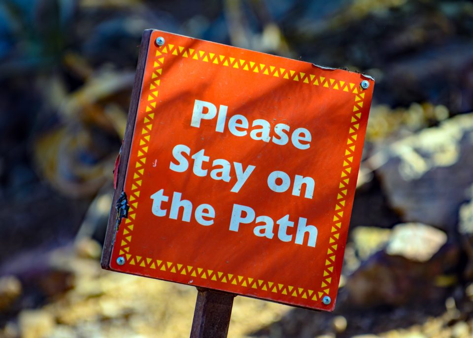 Oranje bord met de tekst: Please stay on the path; foto van Mark Duffel via Unsplash